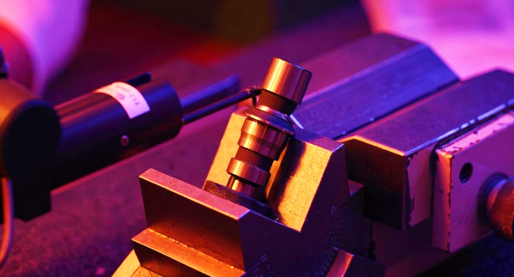Detailansicht eines metallischen Präzisionswerkzeugs in einer Werkstatt, beleuchtet mit violettem Licht